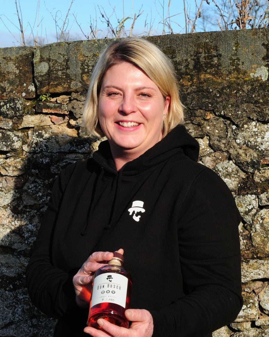 Johanna von Don Drinks mit einer Flasche Don Busco vor einer Weinbergsmauer in Rheinhessen